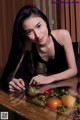 A woman sitting at a table with a basket of fruit.