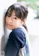 A young girl leaning against a wall with her hand on her hip.