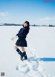 A woman in a school uniform is standing in the snow.