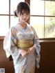 A woman in a kimono standing in front of a window.