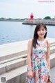 A woman in a floral dress standing by the water.