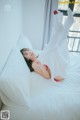 A woman laying on a bed in a white dress.