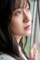 A woman with long brown hair looking out a window.