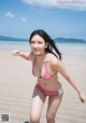 A woman in a pink bikini standing on a beach.