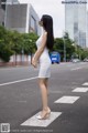 A woman in a white dress standing on a crosswalk.