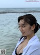 A woman in a black and white bikini standing on the beach.