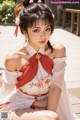 A woman in a white and red dress sitting on a bench.