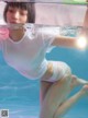 A woman in a white shirt is underwater in a pool.