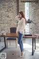 A woman standing in front of a wooden table.