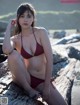 A woman in a red bikini sitting on a log.