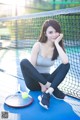 A woman sitting on a tennis court next to a tennis racket.