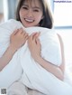 A woman sitting on a bed holding a pillow.