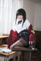 A woman sitting on top of a desk in a classroom.