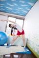 A woman in a white shirt and red shorts doing a yoga pose.