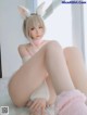 A woman in a bunny costume is sitting on a bed.