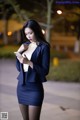 A woman in a blue suit is looking at her phone.