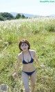 A woman in a blue bikini standing in a field.