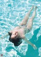 A woman floating in a swimming pool with her eyes closed.