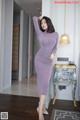 A woman in a purple dress standing in a room.