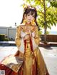 A woman in a chinese dress standing next to a tree.