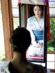 A woman in a kimono looking at herself in a mirror.