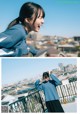 A woman in a blue sweatshirt and black skirt standing on a balcony.